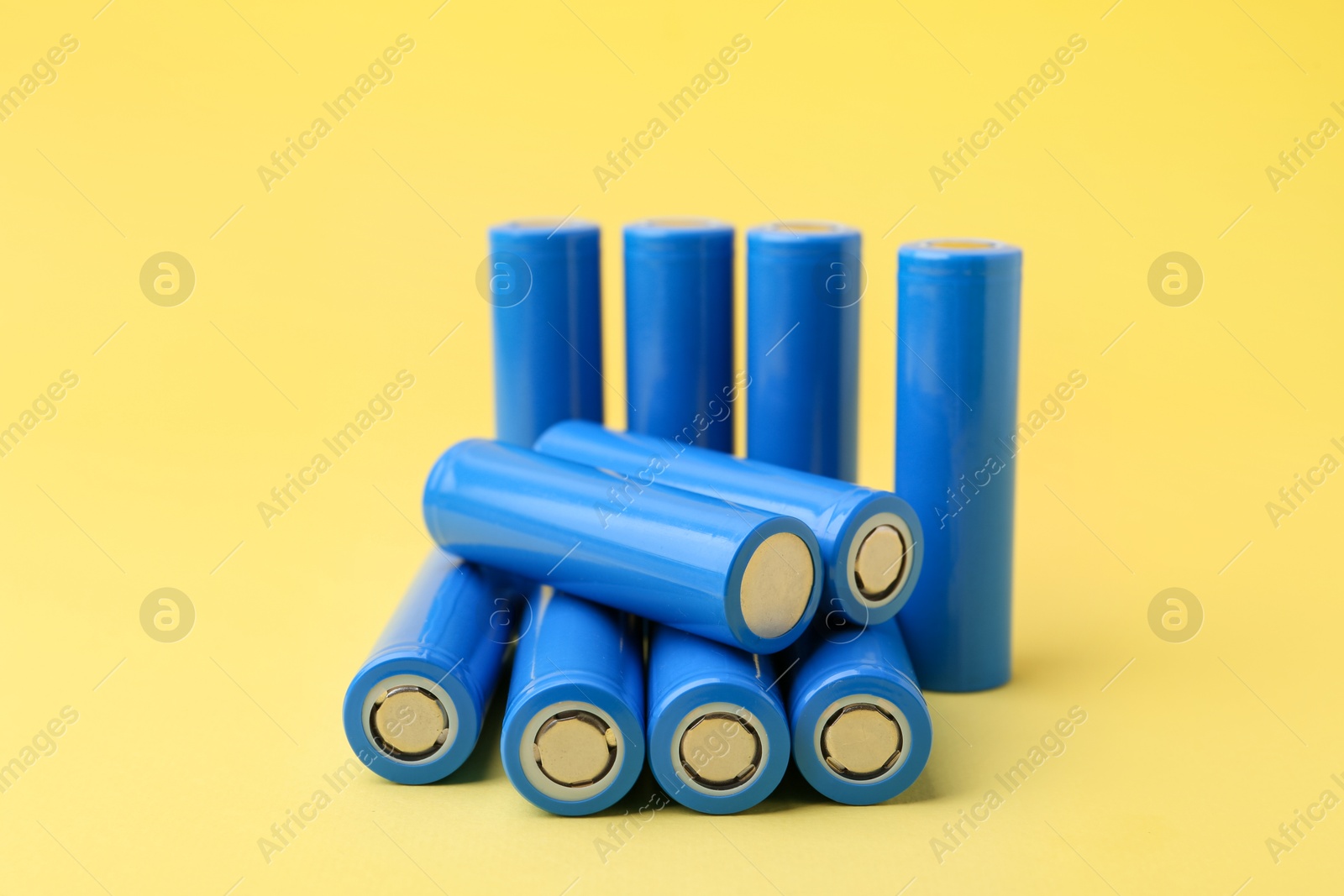 Photo of Many AA cell batteries on yellow background, closeup