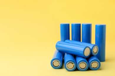 Photo of Many AA cell batteries on yellow background, closeup. Space for text