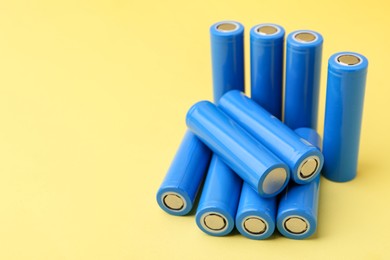 Photo of Many AA cell batteries on yellow background, closeup. Space for text