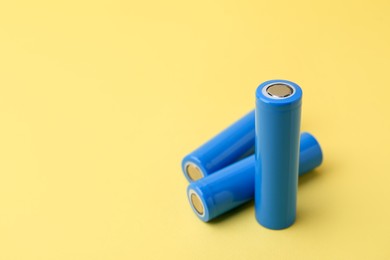 Photo of Three AA cell batteries on yellow background, closeup. Space for text