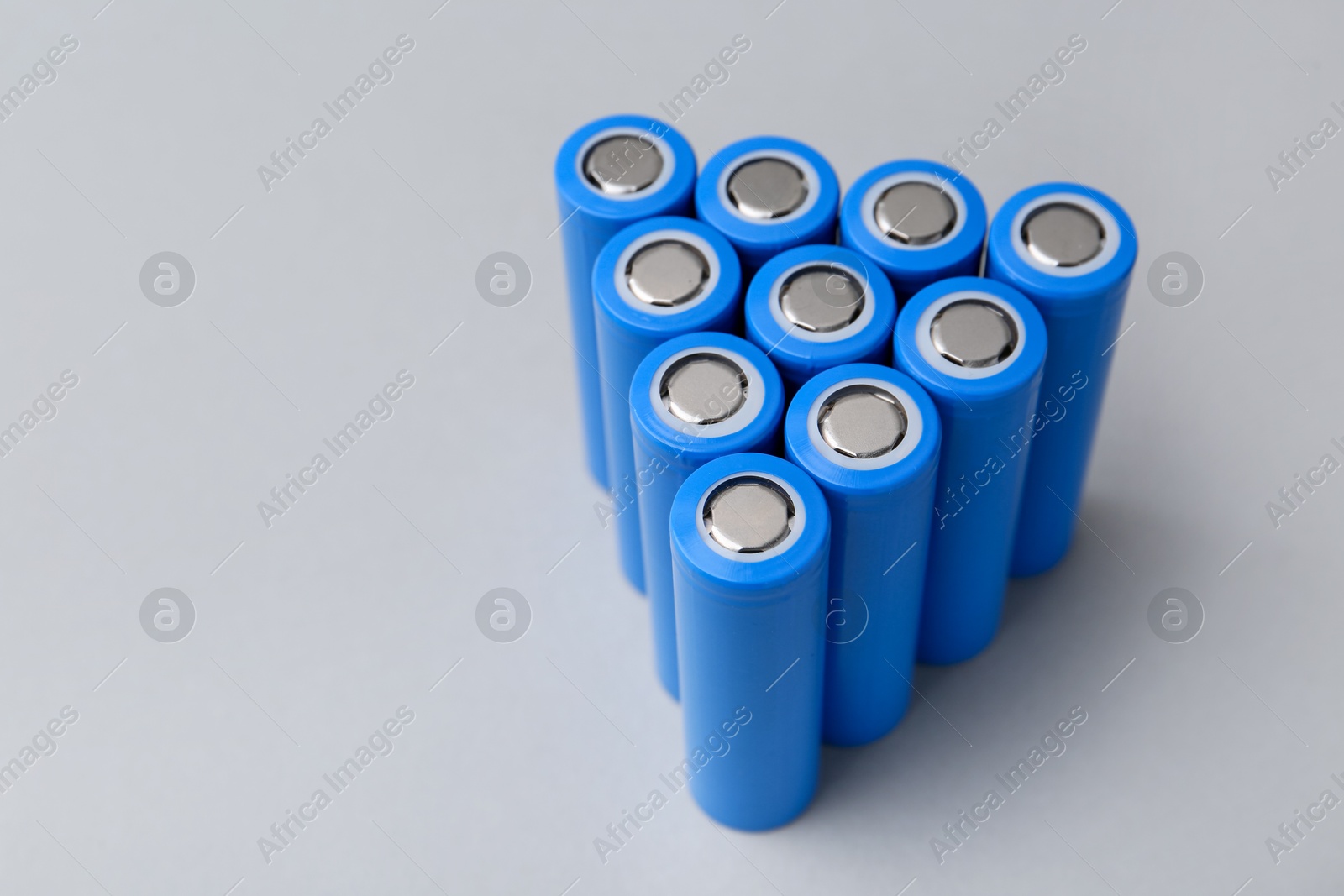 Photo of Many AA cell batteries on light grey background, closeup. Space for text