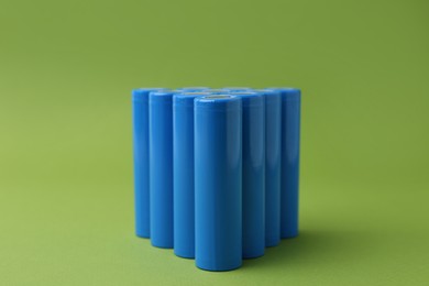 Photo of Many AA cell batteries on green background, closeup