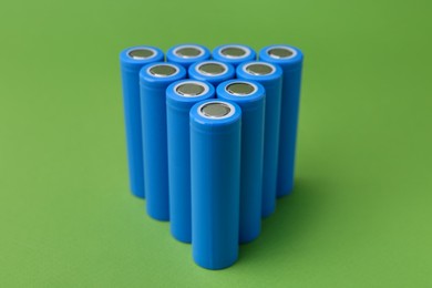 Photo of Many AA cell batteries on green background, closeup