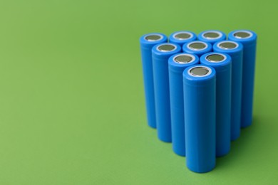 Photo of Many AA cell batteries on green background, closeup. Space for text