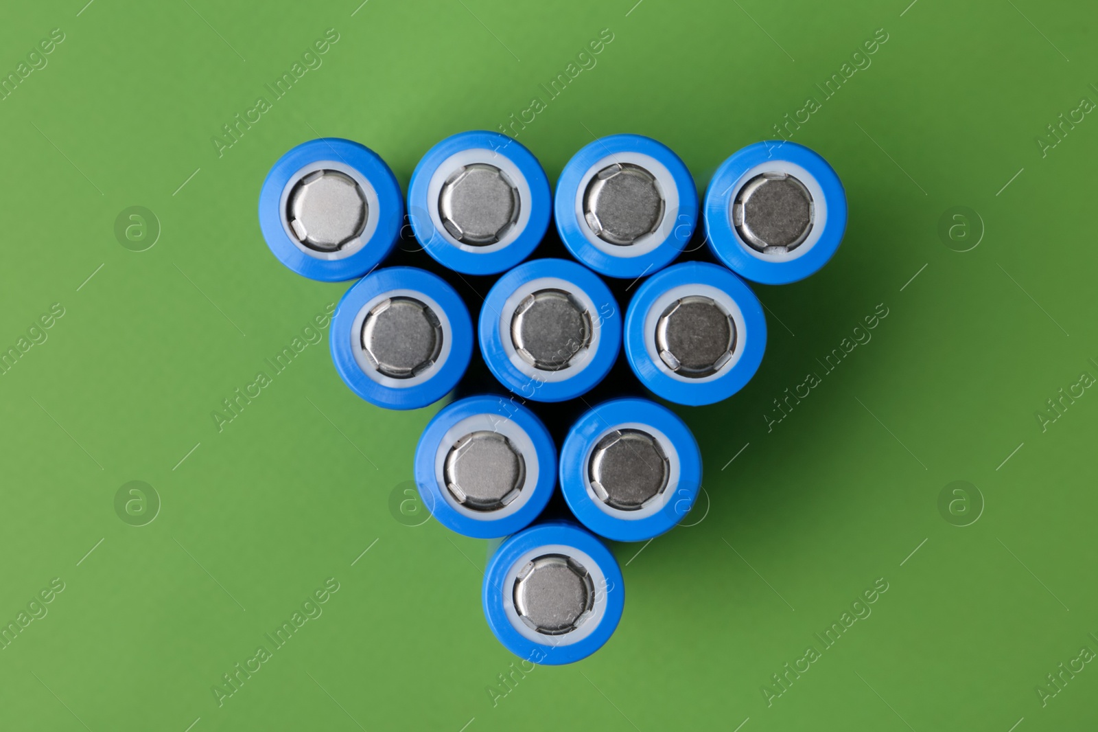 Photo of Many AA cell batteries on green background, top view