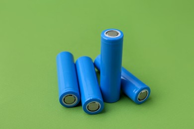 Photo of Many AA cell batteries on green background, closeup