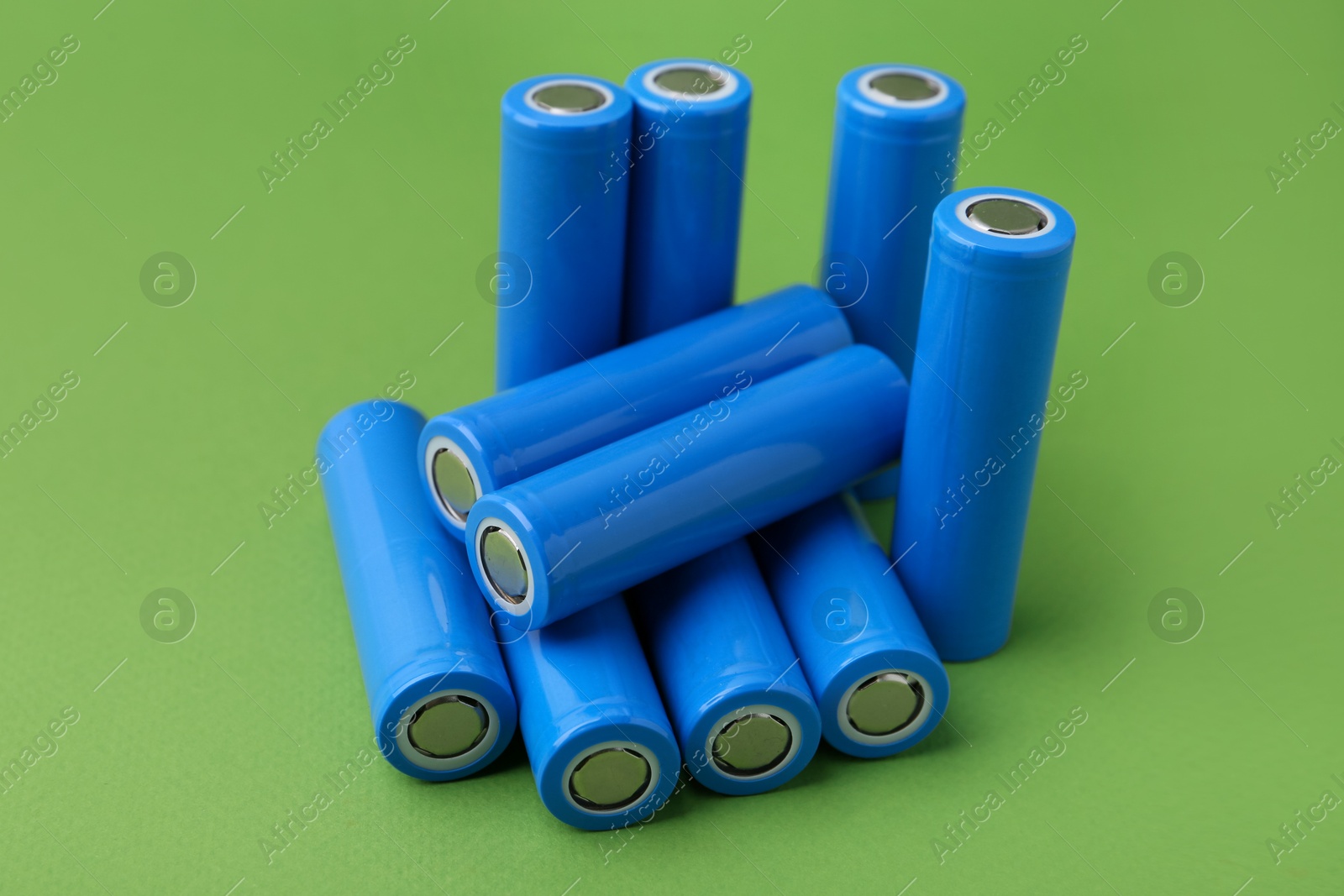 Photo of Many AA cell batteries on green background, closeup