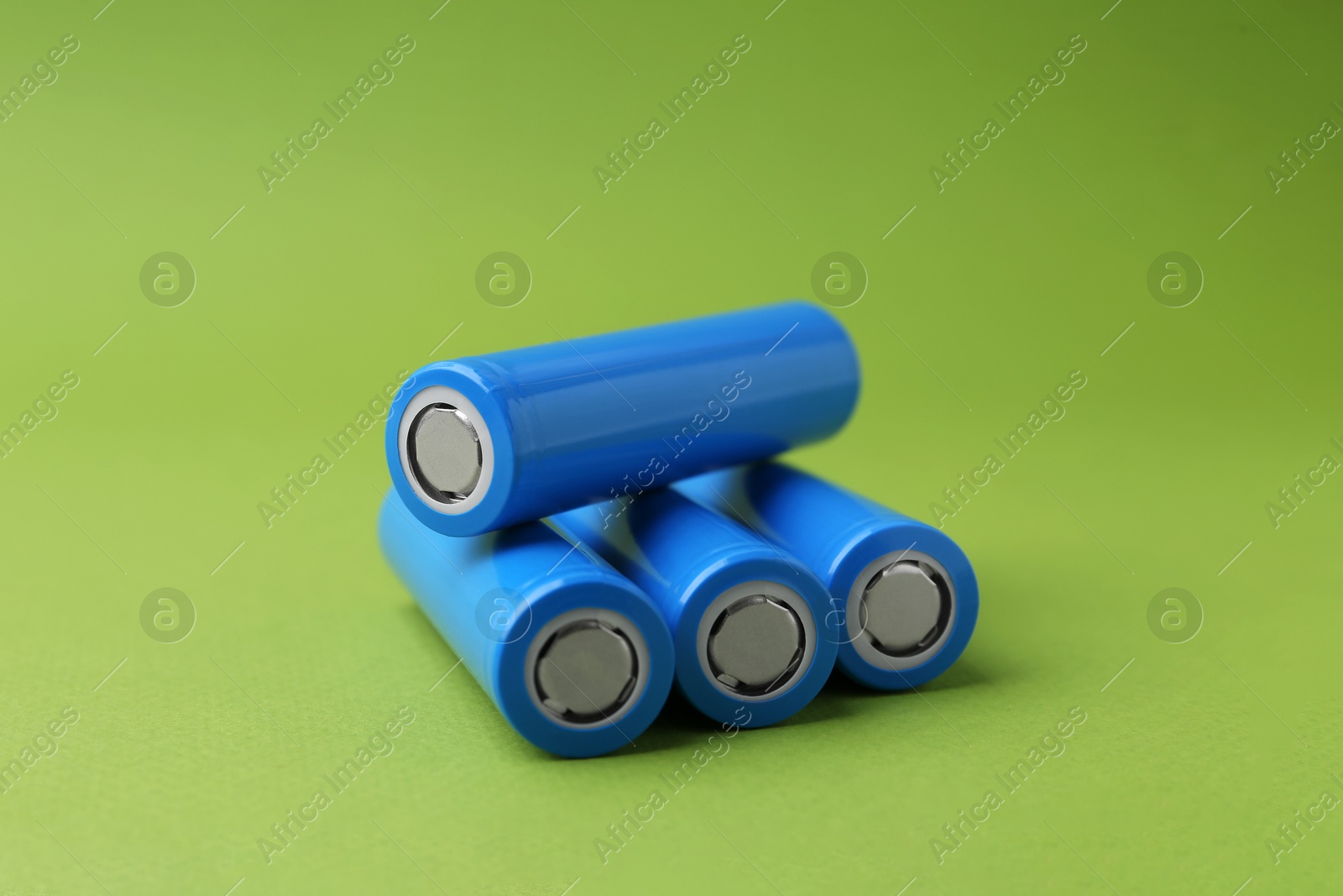 Photo of Many AA cell batteries on green background, closeup. Space for text