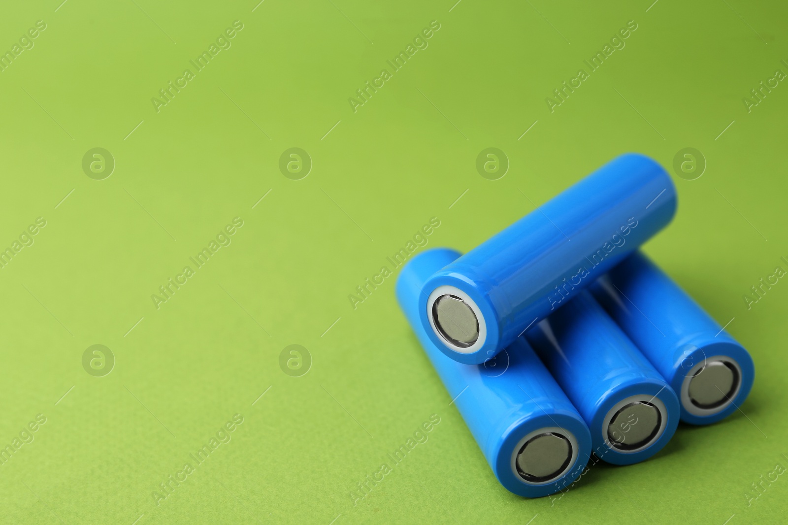 Photo of Many AA cell batteries on green background, closeup. Space for text