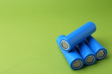 Photo of Many AA cell batteries on green background, closeup. Space for text