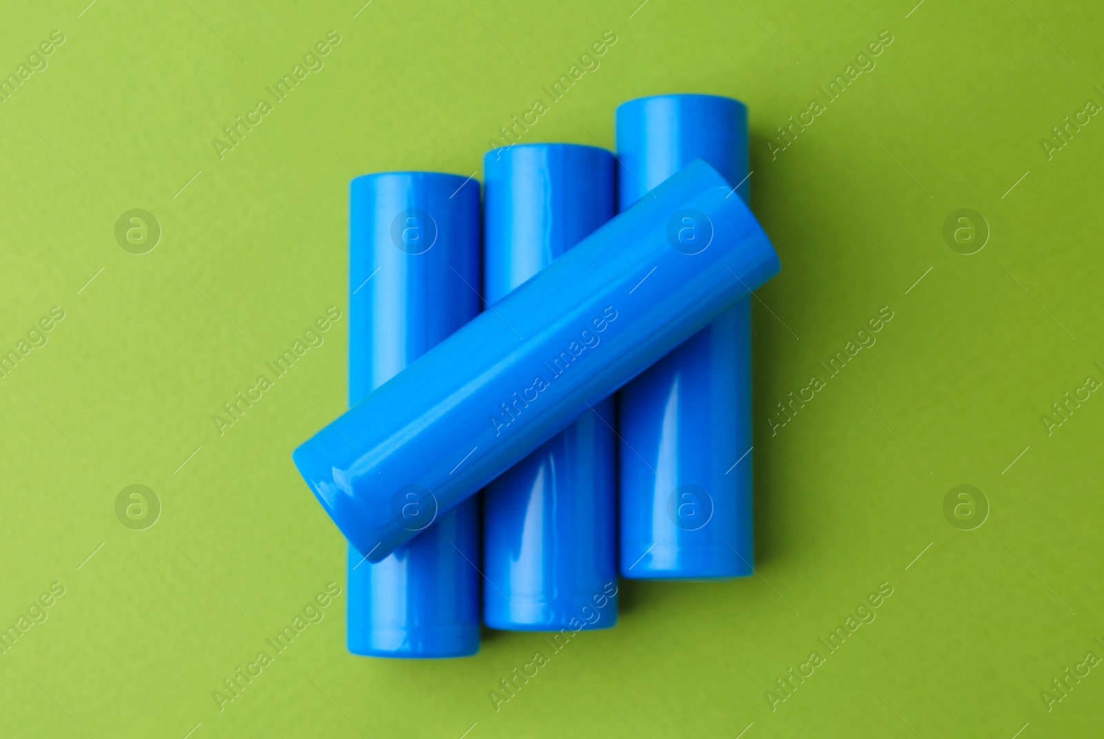 Photo of Many AA cell batteries on green background, top view