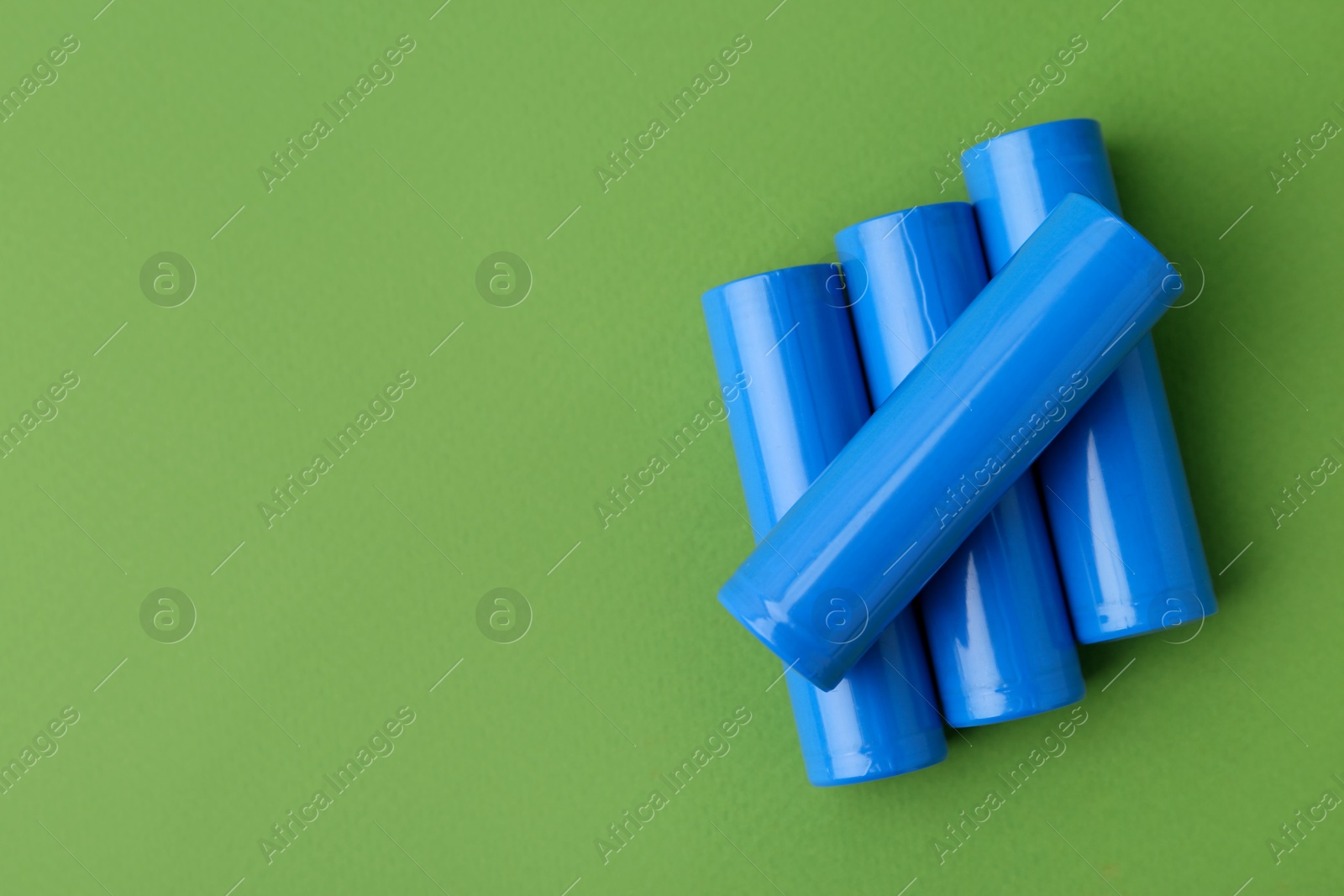 Photo of Many AA cell batteries on green background, top view. Space for text