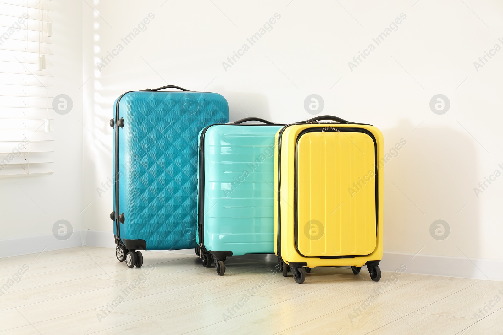 Photo of Colorful suitcases on floor near white wall