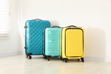 Photo of Colorful suitcases on floor near white wall