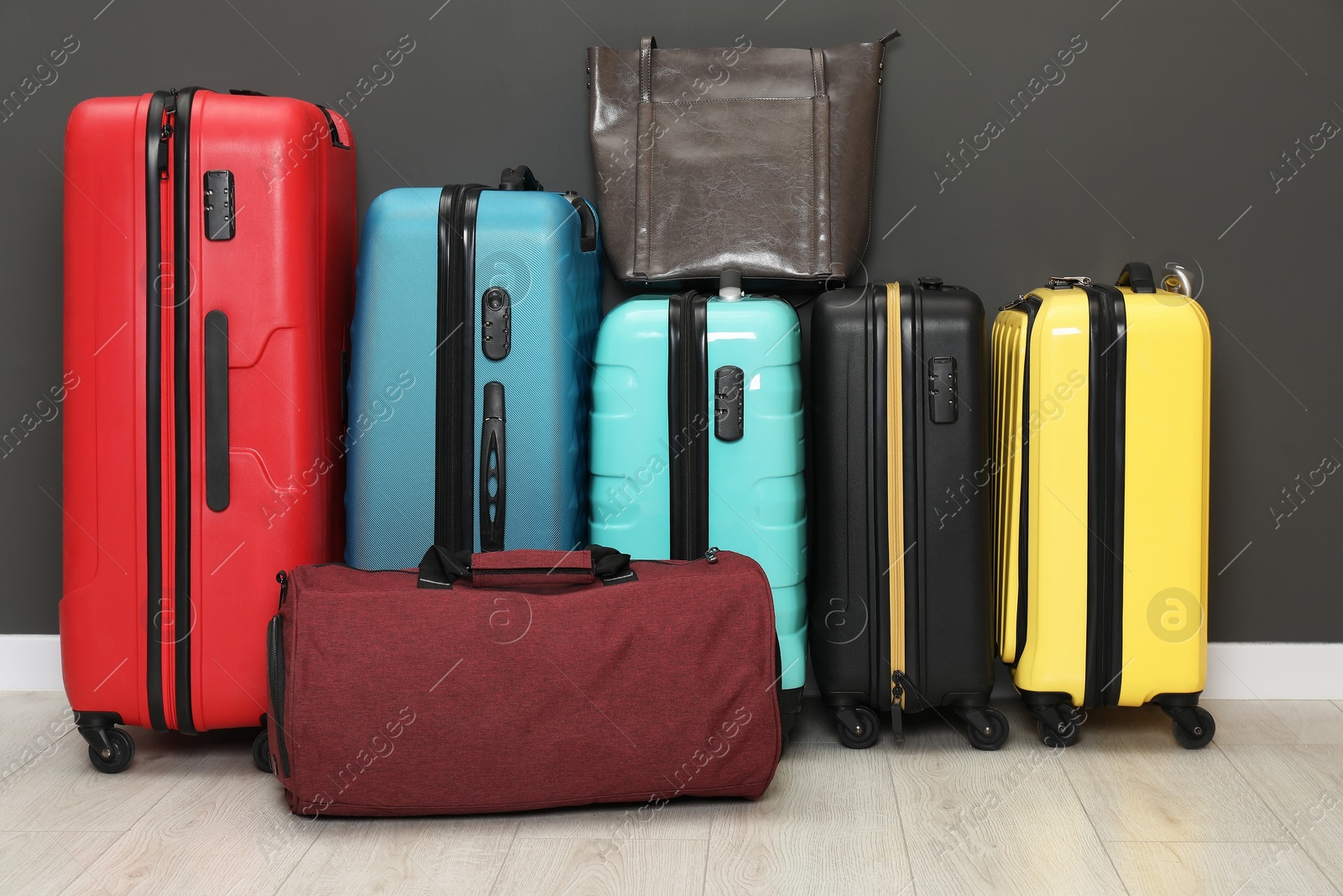 Photo of Colorful suitcases and bags on floor near black wall