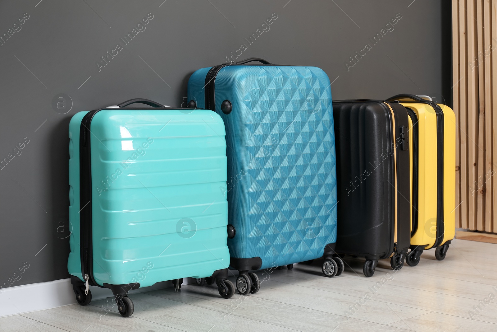 Photo of Colorful suitcases on floor near black wall