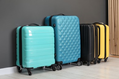 Photo of Colorful suitcases on floor near black wall