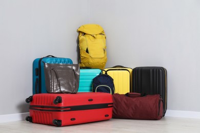 Photo of Colorful suitcases, backpacks and bags on floor near light wall