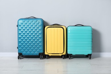 Photo of Many colorful suitcases on floor near light wall