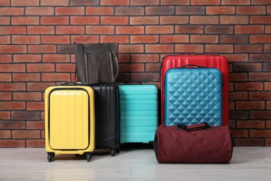 Photo of Many colorful suitcases and bags on floor near brick wall