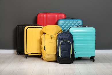 Photo of Colorful suitcases and backpacks on floor near black wall