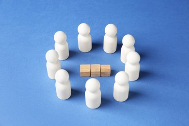 Photo of Competition concept. Human figures around wooden cubes on blue background