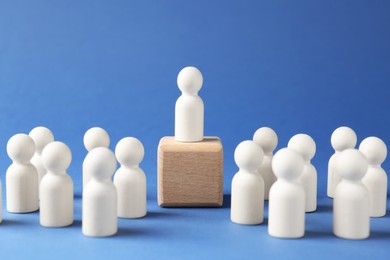 Photo of Competition concept. Human figure on wooden cube and other ones behind against blue background