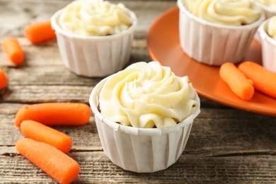 Photo of Delicious carrot muffins and fresh vegetables on wooden table, closeup