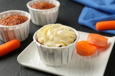 Photo of Delicious carrot muffins with fresh vegetable on grey table, closeup