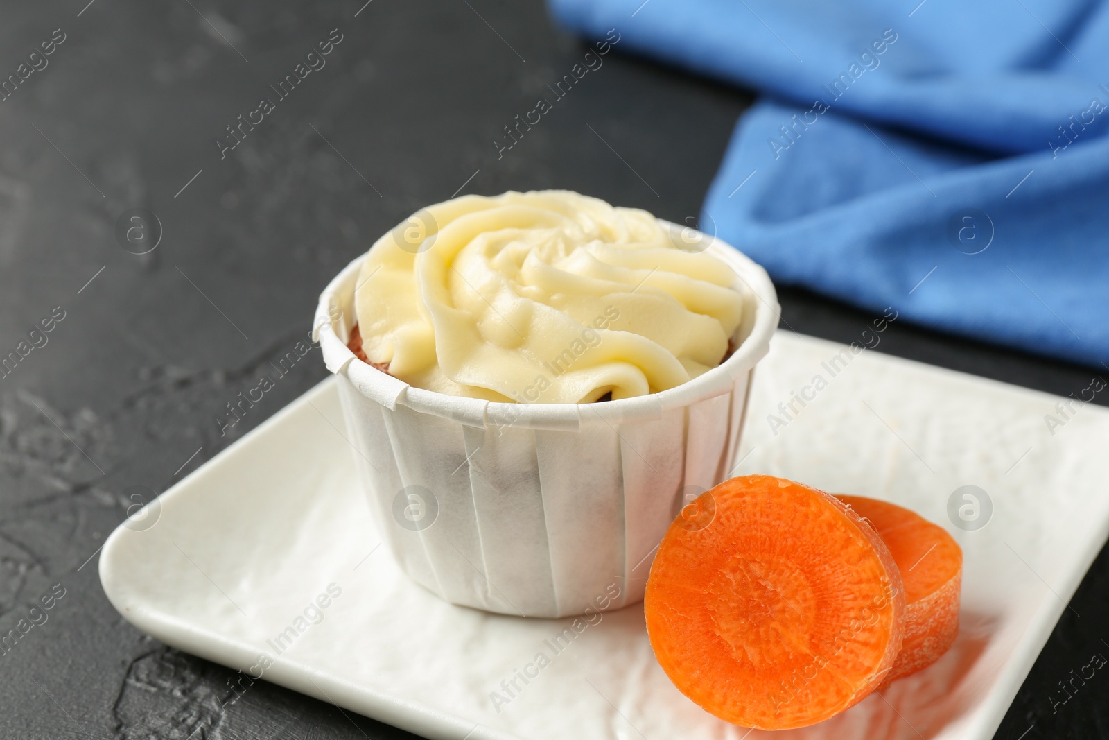 Photo of Tasty carrot muffin with fresh vegetable on grey table, closeup