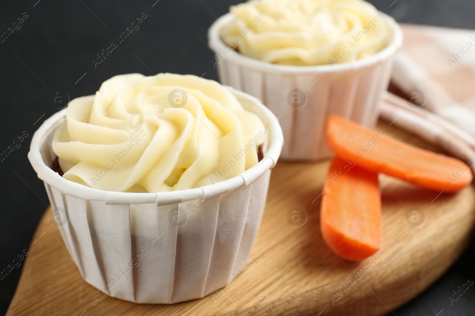 Photo of Tasty carrot muffins with fresh vegetable on black table, closeup