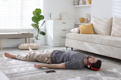 Photo of Man in headphones meditating on floor at home