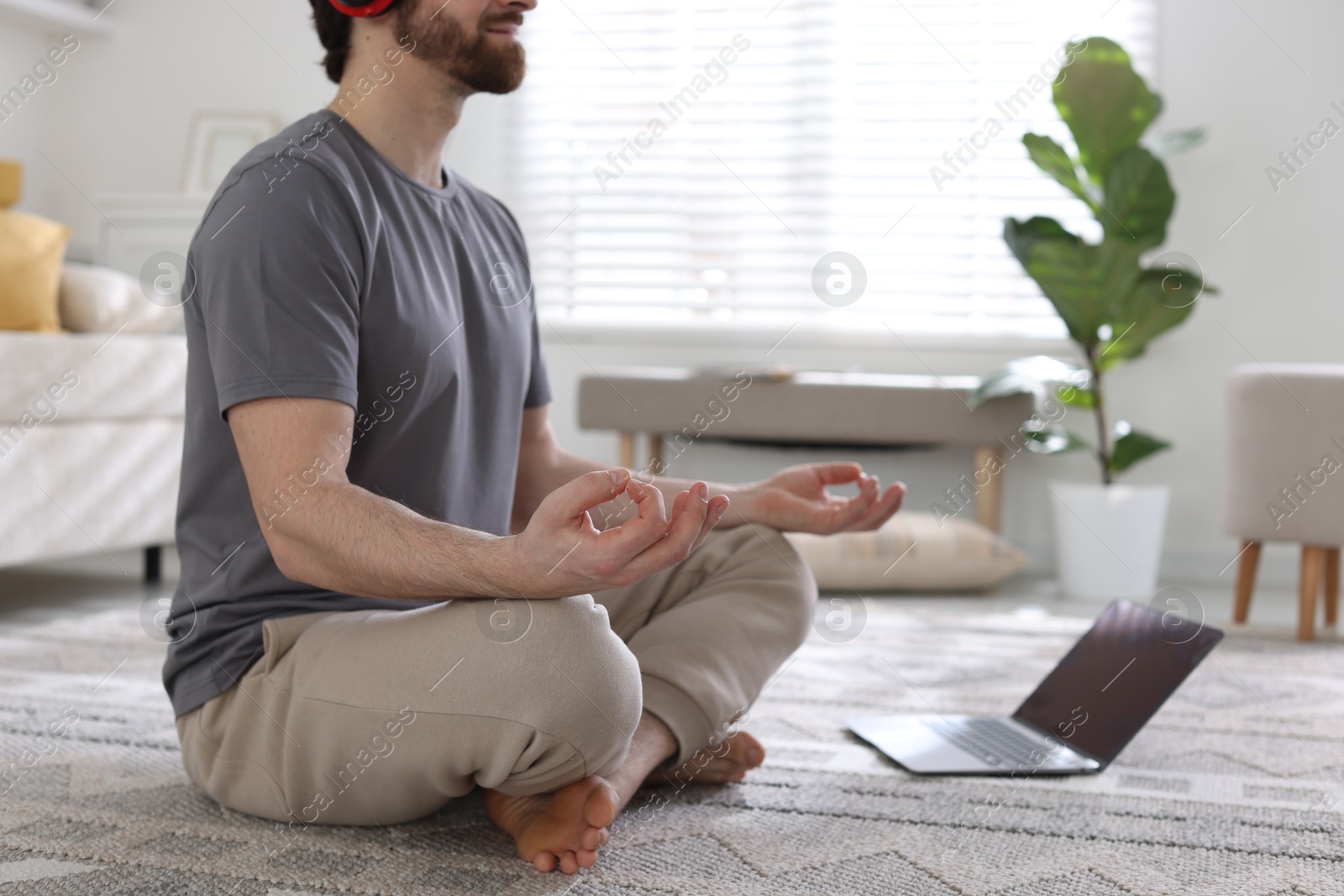 Photo of Man with laptop meditating on floor at home, closeup