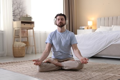 Photo of Man in headphones meditating on floor at home