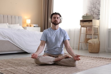 Photo of Man in headphones meditating on floor at home