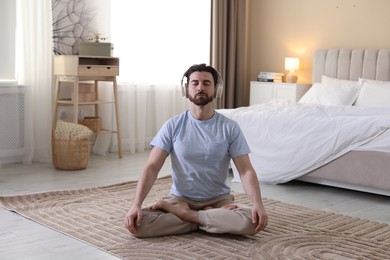 Photo of Man in headphones meditating on floor at home