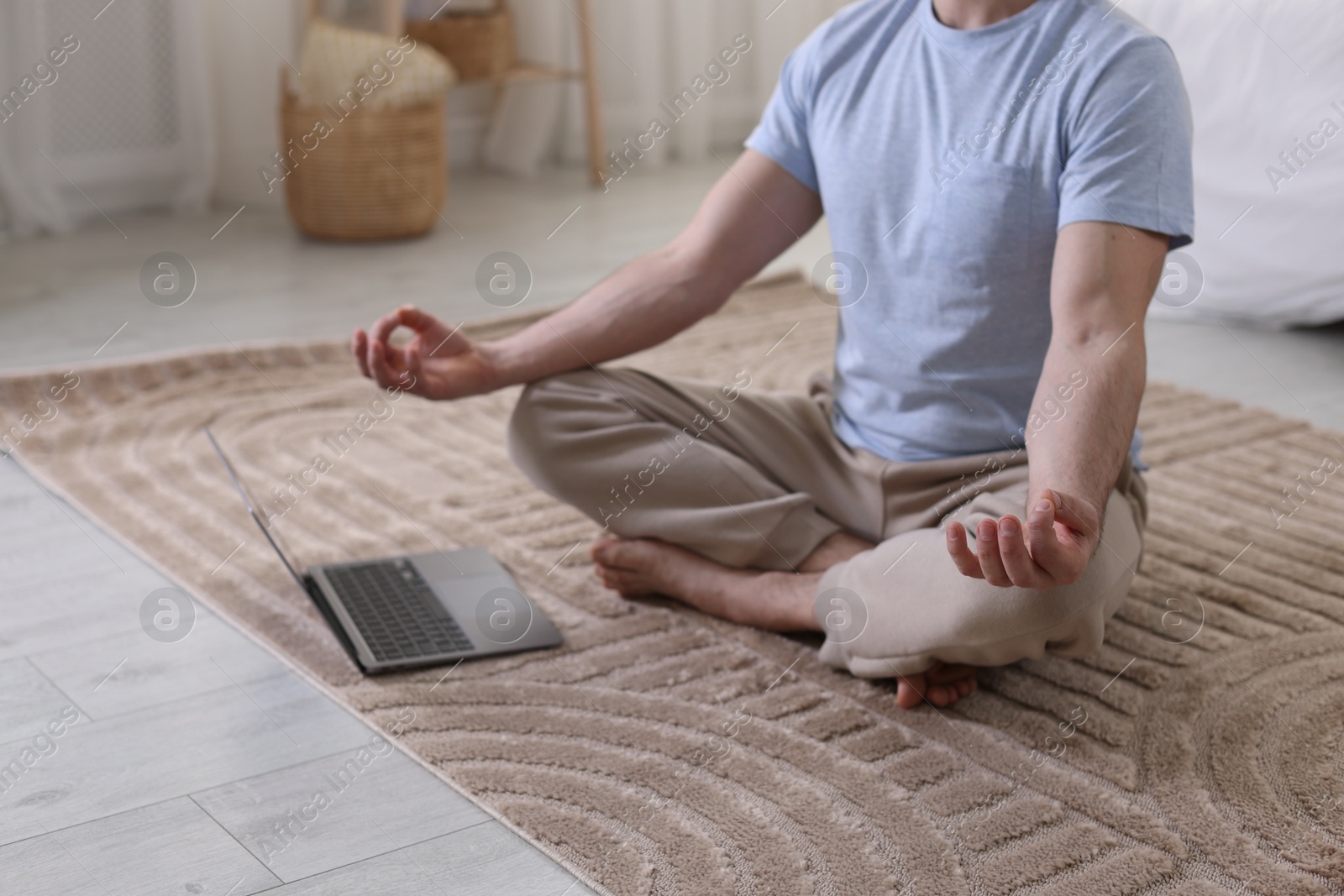 Photo of Man meditating near laptop on floor at home, closeup