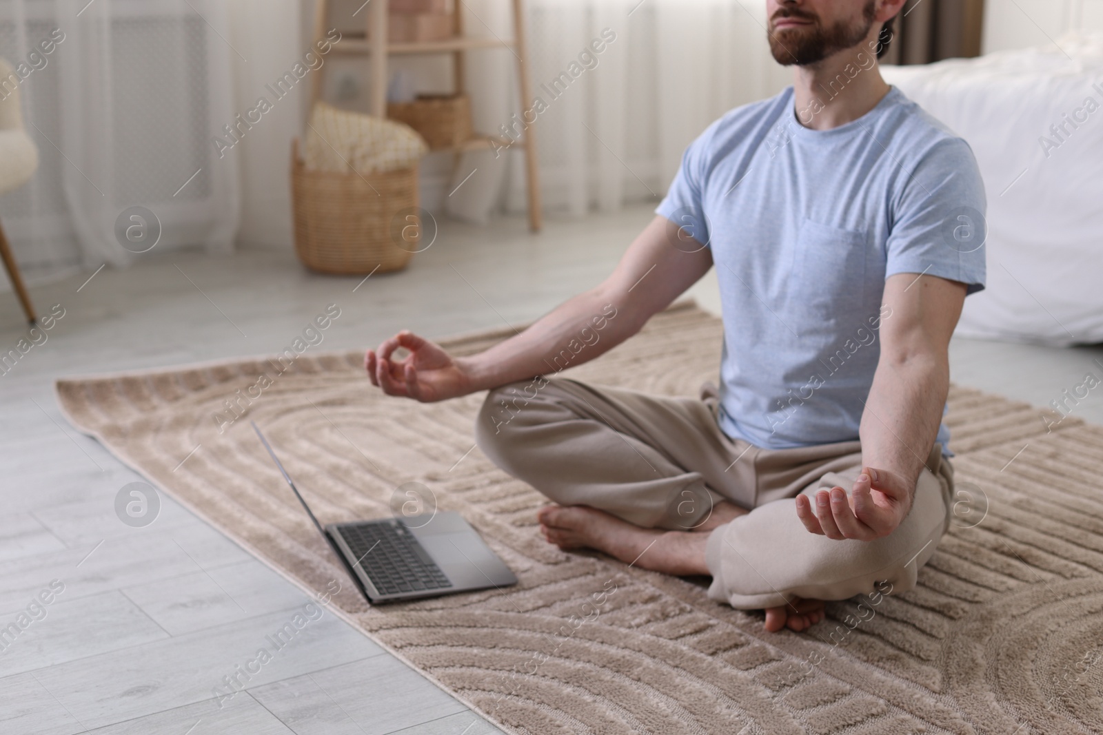 Photo of Man meditating near laptop on floor at home, closeup