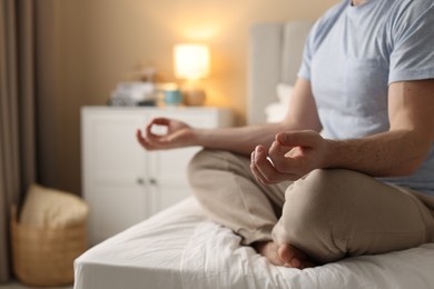 Photo of Man meditating on bed at home, closeup. Space for text