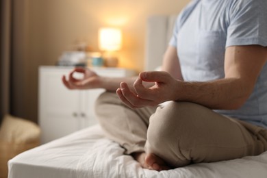 Photo of Man meditating on bed at home, closeup. Space for text