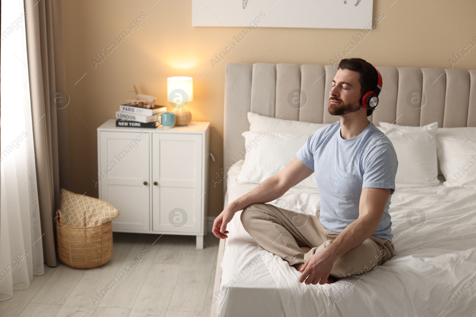 Photo of Man in headphones meditating on bed at home