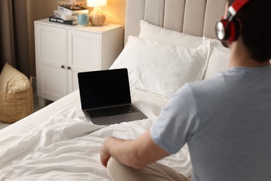 Photo of Man meditating near laptop on bed at home, selective focus