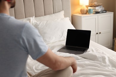 Photo of Man meditating near laptop on bed at home, selective focus