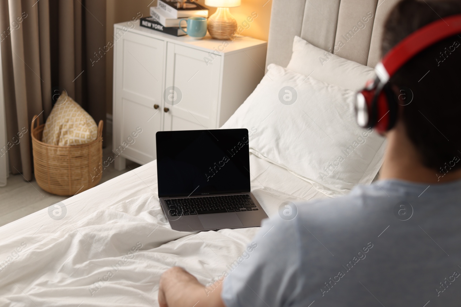 Photo of Man meditating near laptop on bed at home, selective focus