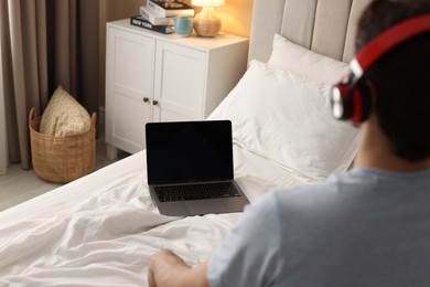 Photo of Man meditating near laptop on bed at home, selective focus