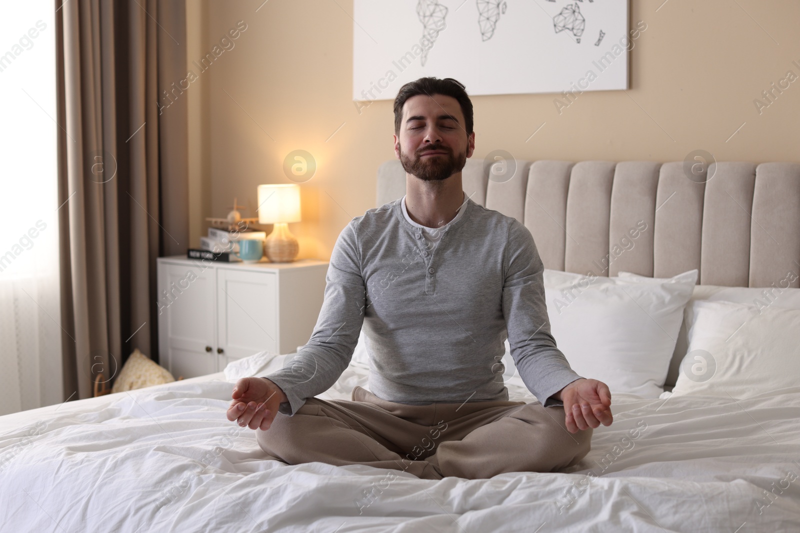 Photo of Handsome man meditating on bed at home