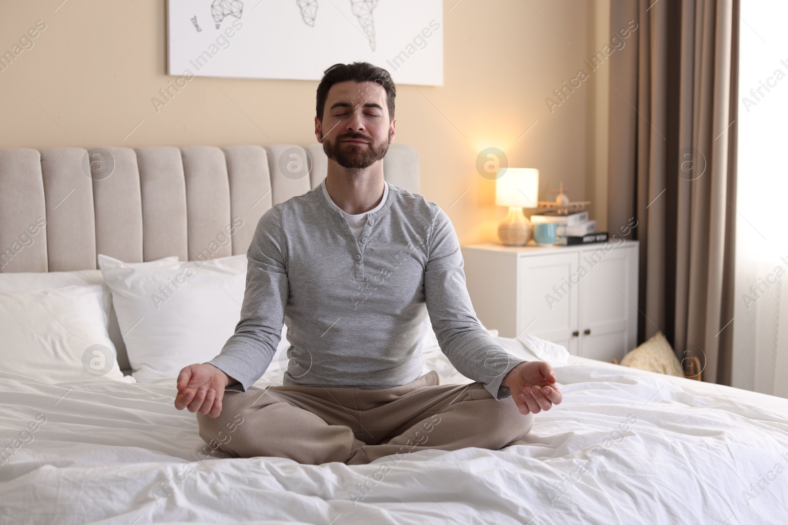 Photo of Handsome man meditating on bed at home