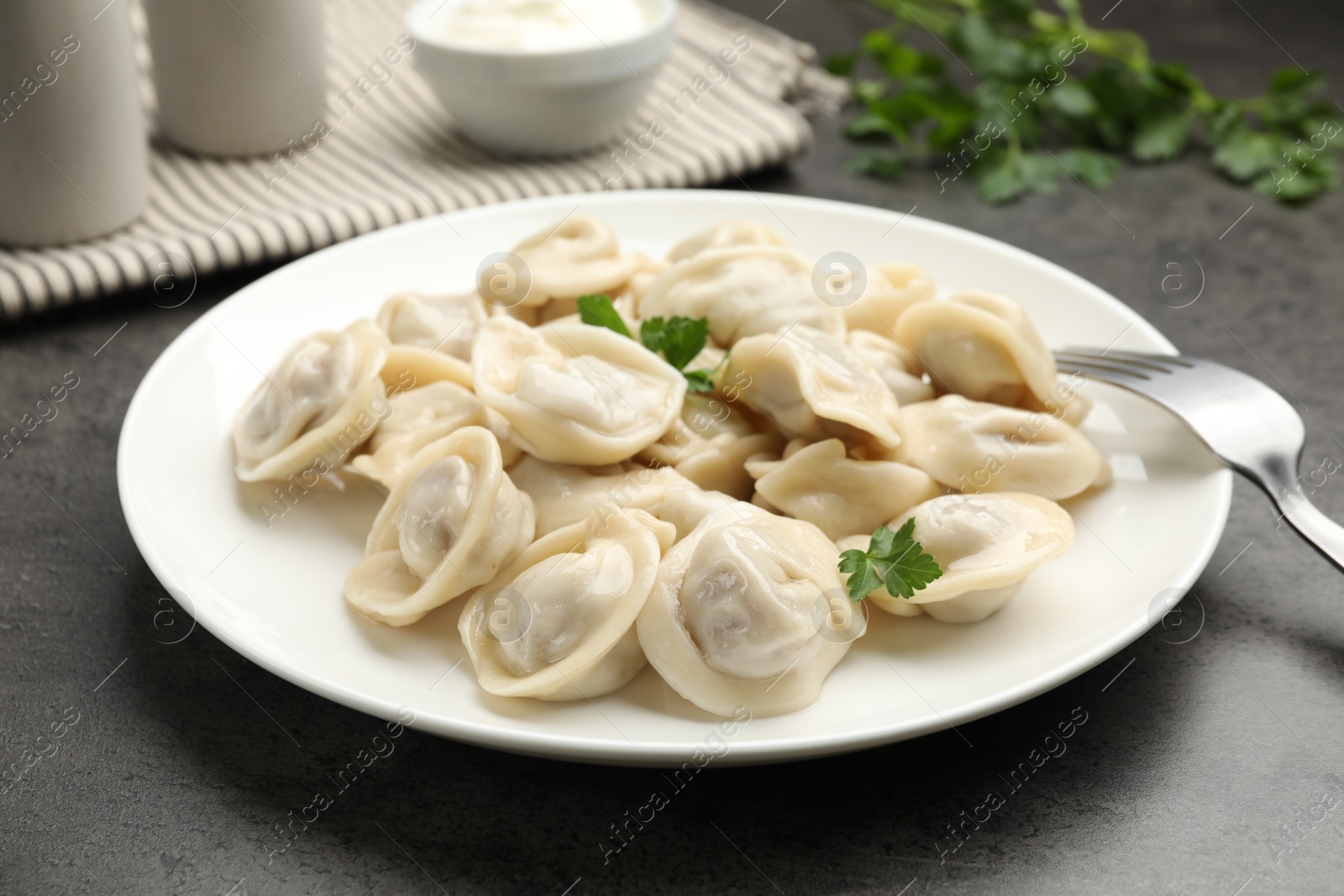 Photo of Delicious dumplings with fresh parsley served on grey table, closeup