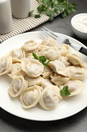 Photo of Delicious dumplings with fresh parsley served on grey table, closeup