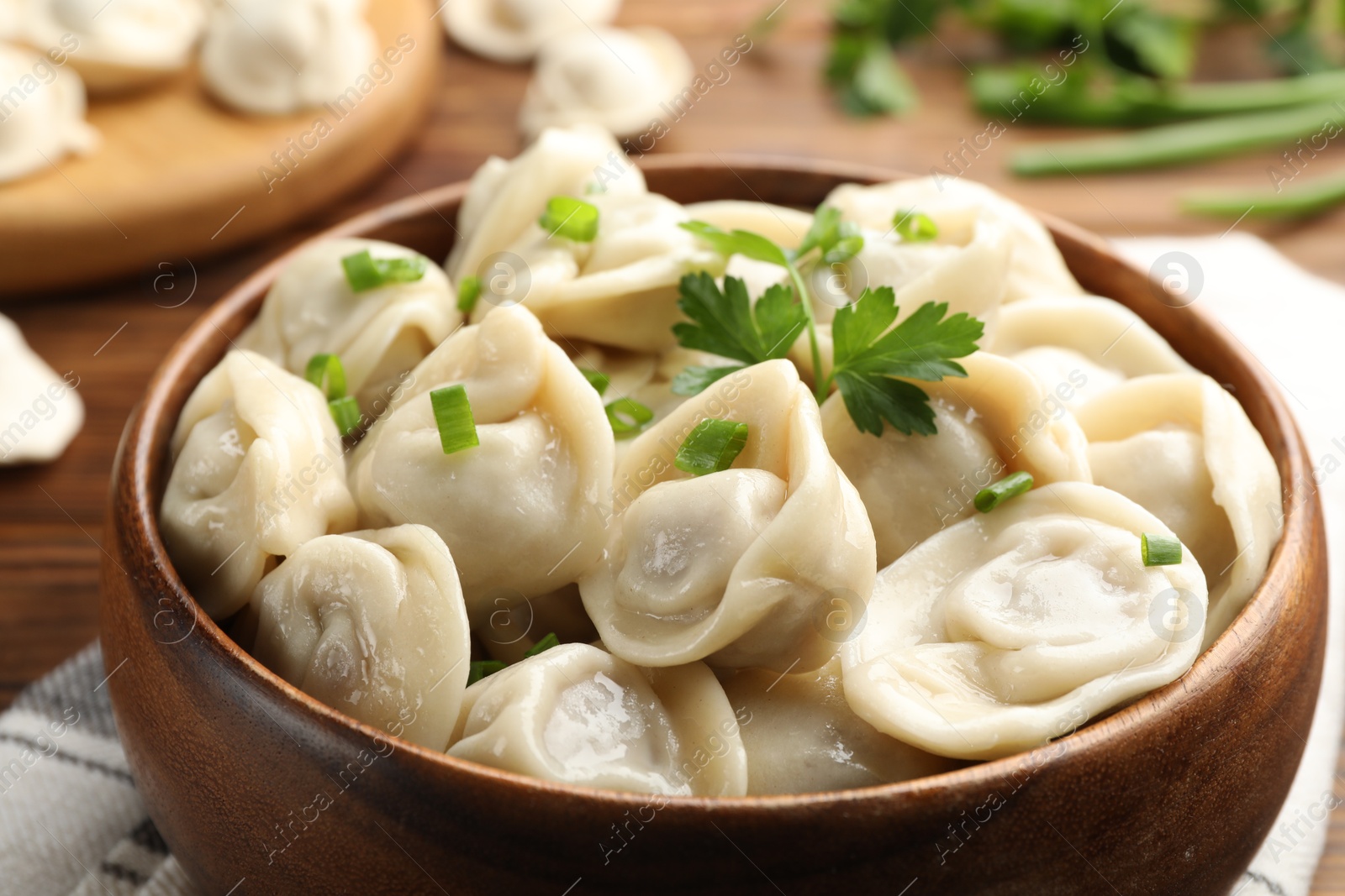 Photo of Delicious dumplings with fresh green onion and parsley on table, closeup